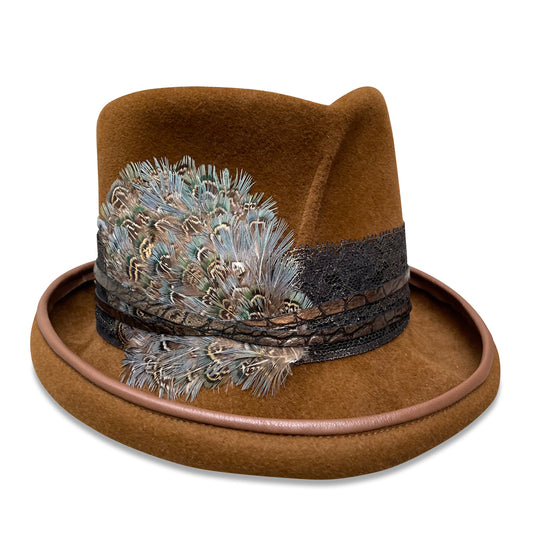 A luxurious top hat in bronze velour felt with matching lambskin piping around the brim. The hat features a decorative band of bronze lace layered over faux crocodile skin, and is adorned with a cluster of multi-colored pheasant feathers. The design is from Cha Cha's House of Ill Repute, a woman-owned millinery in New York City.