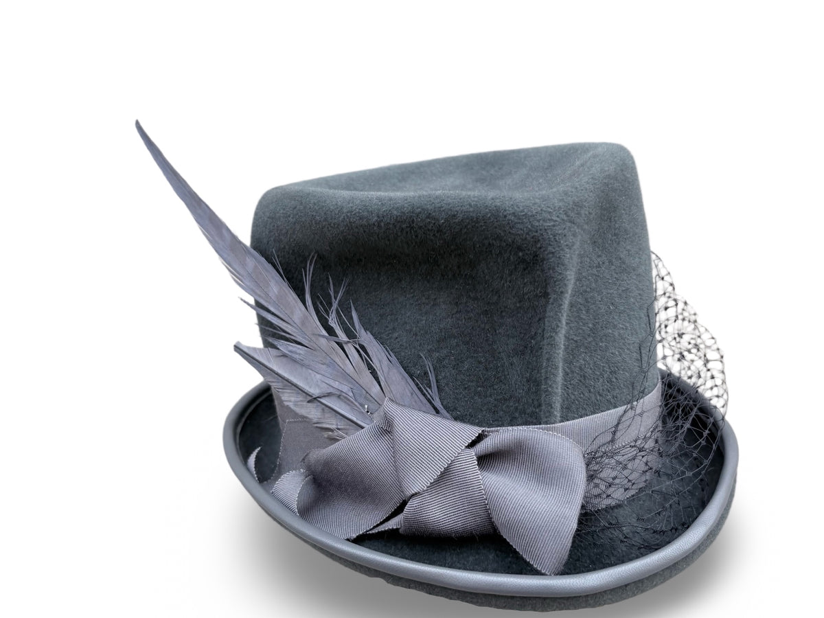 A dark gray felt top hat with a matching gray ribbon bow, feather accent, and silver mesh veil, set against a plain white background.