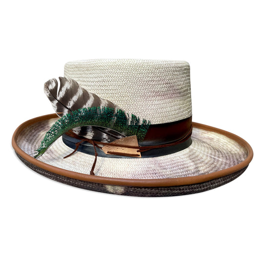 A tie-dye Gambler hat with a 3-inch brim and lambskin piping, adorned with an ombre silk band, suede cord, brass hardware, and accentuated with a turkey wing feather. Created by Cha Cha's House of Ill Repute, a woman-owned millinery in New York City