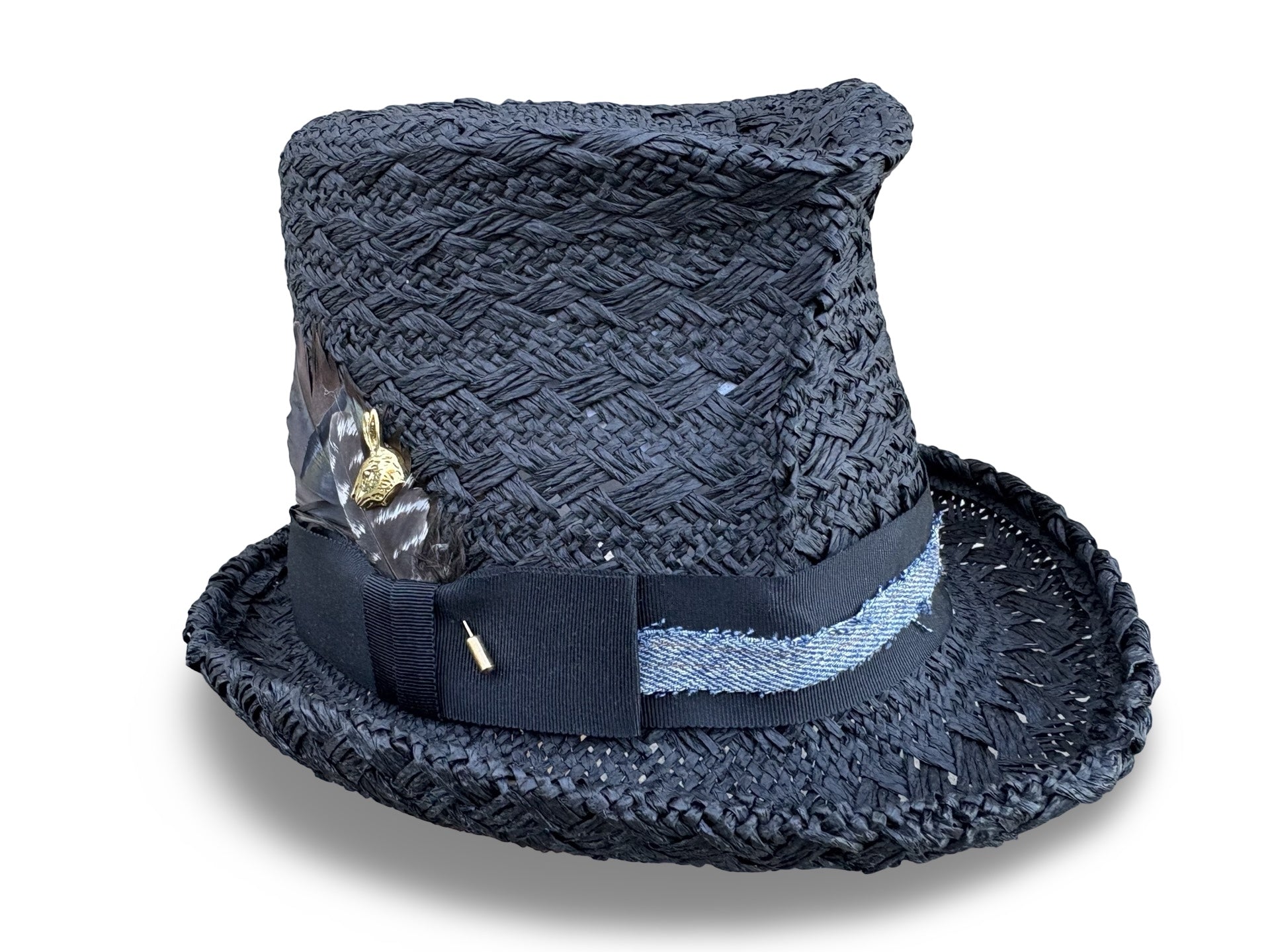 Black crochet straw hat with decorative band and feather on a white background