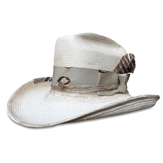 A distressed ivory Shantung straw cowboy hat with a snakeskin brim strip and turkey feather from Cha Cha's House of Ill Repute in New York City