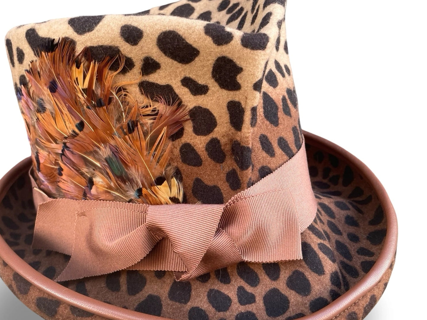 Leopard print hat with feather and ribbon on a white background