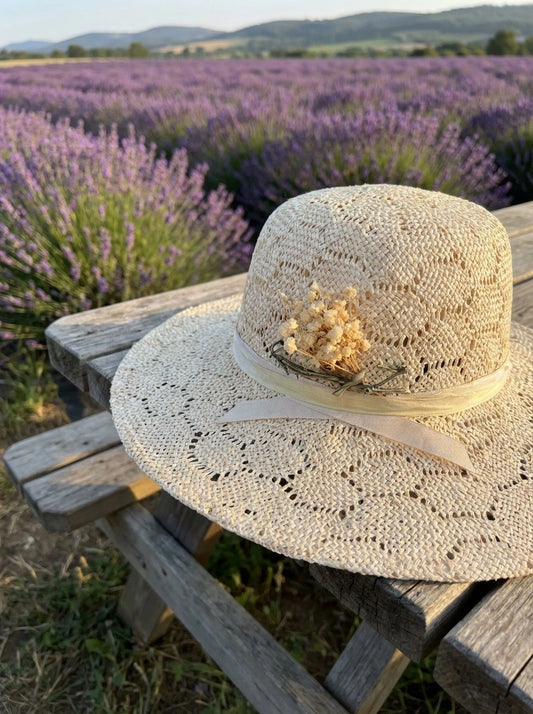 Straw hat with a decorative flower on a wooden table in front of a lavender field