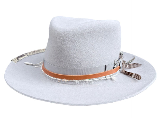 A light gray felt cowboy hat with a tan leather band, silver trim, and decorative feathers on the side, shown against a plain white background.