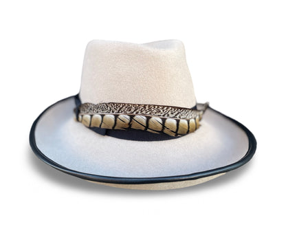 Alabaster Fedora trimmed with black grosgrain and pheasant tail. Brim is piped with black lamb skin