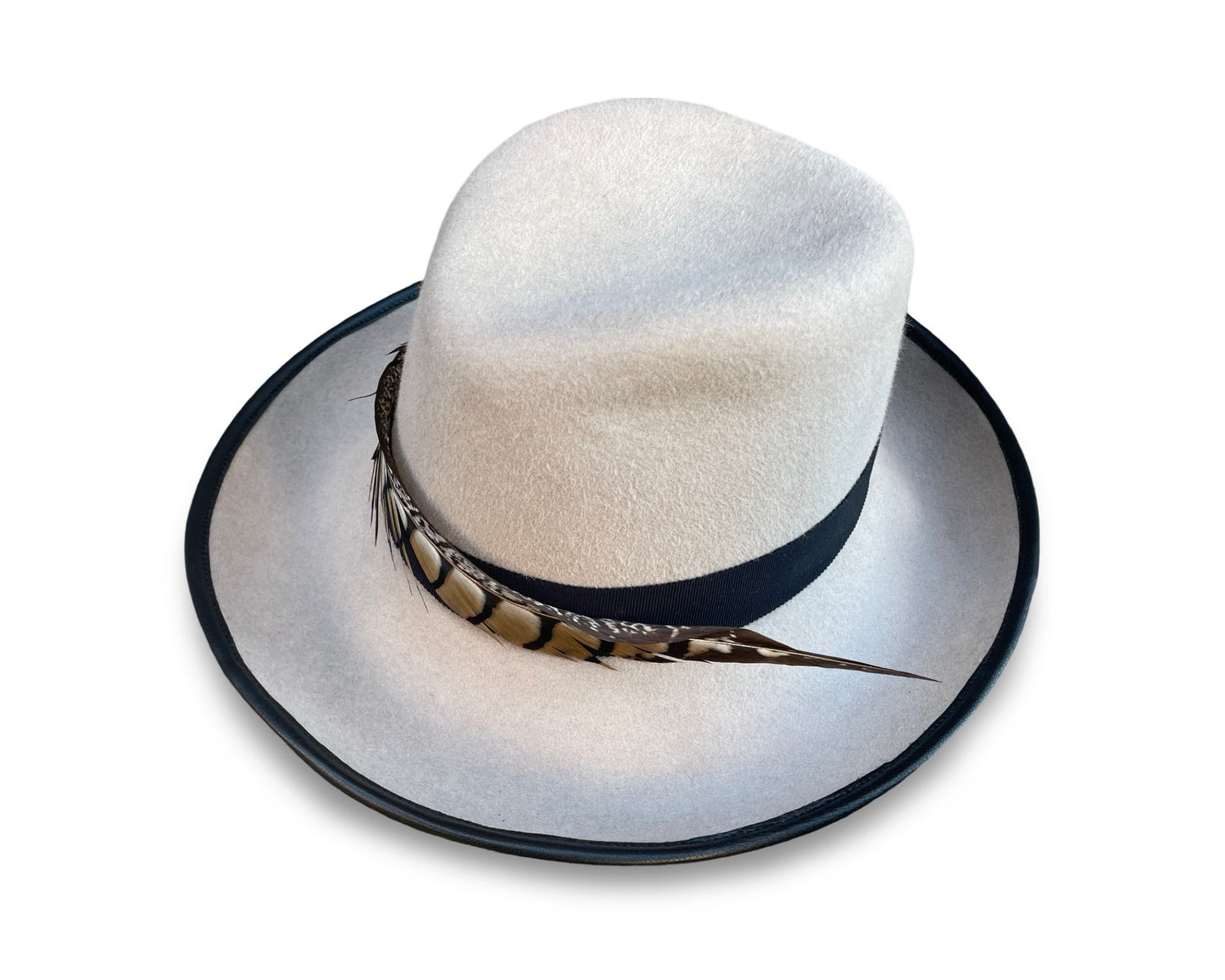 Alabaster Fedora trimmed with black grosgrain and pheasant tail. Brim is piped with black lamb skin