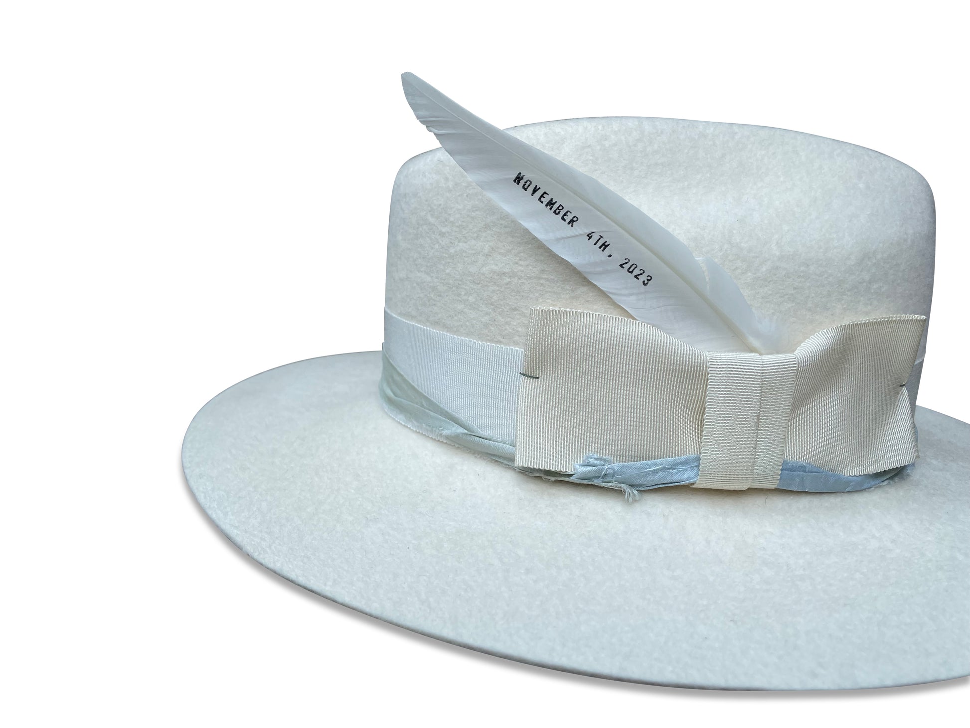 Custom-made 'June' ivory cowboy hat for weddings, featuring a unique feather and recycled silk accents