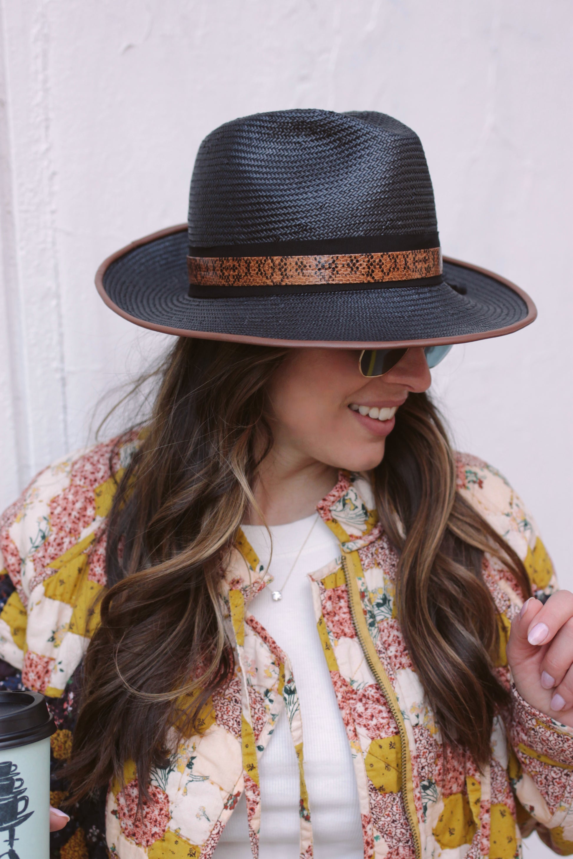 Black straw fedora with chocolate leather piping. Black ribbon trim overlaid with lizard layer. Center dent crown with three inch brim. Shown on model.
