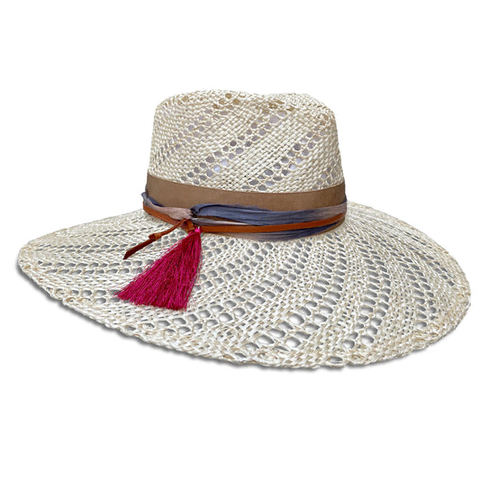 Wide brim straw hat trimmed with camel ribbon, silk sari fabric, leather cord  &  a hot pink tassel.  Straw is woven  with an open weave swirl pattern . Right side view. 