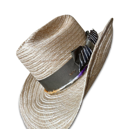 straw cowboy hat for women, named La Chatte, showcasing handwoven textures, colorful silk yarn embellishments, and a feather detail, emphasizing its bespoke quality