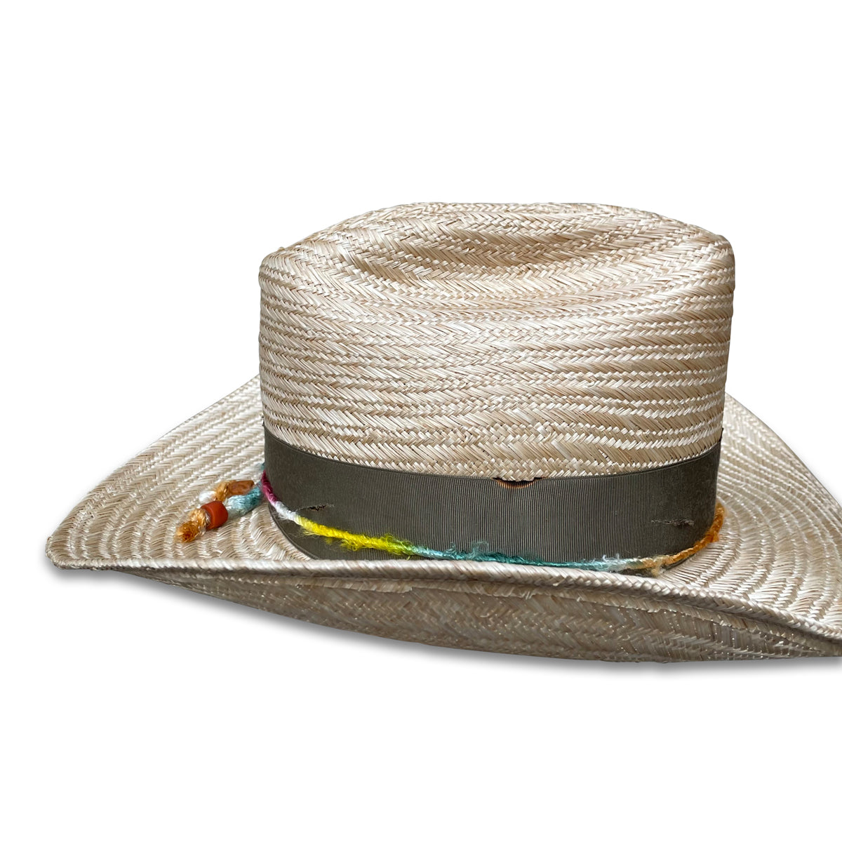Detailed image of a handwoven sisol straw cowboy hat adorned with a multicolored silk yarn and a grosgrain ribbon. A sustainably sourced turkey feather from Vermont decorates the hat.